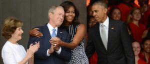 SEPTEMBER 24: President Barack Obama watches first lady Michelle Obama embracing former president George Bush, accompanied by his wife, former first lady Laura Bush, while participating in the dedication of the National Museum of African American History and Culture September 24, 2016 in Washington, DC, before the museum opens to the public later that day. The museum is a Smithsonian Institution museum located on the National Mall featuring African American history and culture in the US. (Photo by Astrid Riecken/Getty Images)
