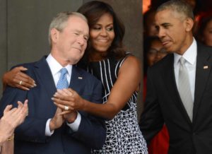 WASHINGTON, DC - SEPTEMBER 24: President Barack Obama watches first lady Michelle Obama embracing former president George Bush, accompanied by his wife, former first lady Laura Bush, while participating in the dedication of the National Museum of African American History and Culture September 24, 2016 in Washington, DC, before the museum opens to the public later that day. The museum is a Smithsonian Institution museum located on the National Mall featuring African American history and culture in the US. (Photo by Astrid Riecken/Getty Images)
