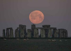 WILTSHIRE, ENGLAND - APRIL 27: The full moon sets behind Stonehenge on April 27, 2021 in Amesbury, England. The pink supermoon will reach peak size in the early hours of Tuesday morning and will shine 30% brighter than a normal full moon. (Photo by Finnbarr Webster/Getty Images)