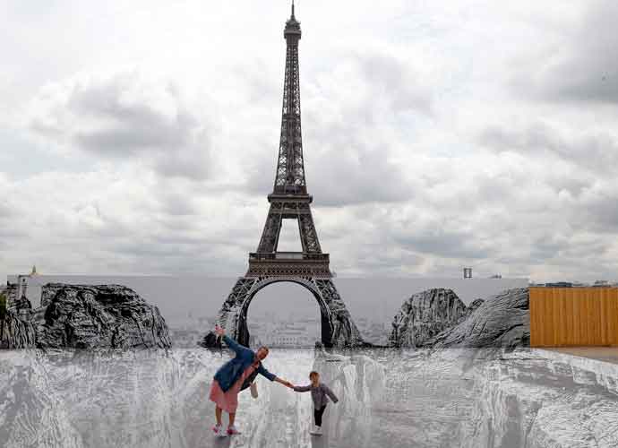 PARIS, FRANCE - JUNE 04: People pose on a trompe-l'oeil art installation by French photographer and street artist Jean Rene, known as JR, set up at the Trocadero parvis in front of the Eiffel Tower on June 04, 2021 in Paris, France. JR has installed a huge photographic collage in front of the Eiffel Tower to create a giant optical illusion through an anamorphosis, a technique that allows to appear or disappear a work. (Photo by Chesnot/Getty Images)