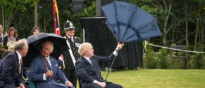 STAFFORD, ENGLAND - JULY 28: Prince Charles, Prince of Wales looks on as (C) British Prime Minister, Boris Johnson (R) opens his umbrella at The National Memorial Arboretum on July 28, 2021 in Stafford, England. The Police Memorial, designed by Walter Jack, commemorates the courage and sacrifice of members of the UK Police service who have dedicated their lives to protecting the public. The memorial is set on grounds landscaped by Charlotte Rathbone within the National Memorial Arboretum and stands along with 350 memorials for the armed forces, civilian organisations and voluntary bodies who have played their part serving the country. (Photo by Christopher Furlong - WPA Pool/Getty Images)