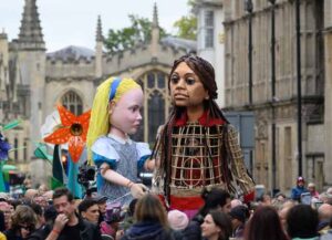 OXFORD, ENGLAND - OCTOBER 26: "Alice" from the Alice in Wonderland story and "Little Amal" are seen on October 26, 2021as they walk through the cectre of Oxford, England. Little Amal, the 3.5 metre-tall puppet representing a migrant Syrian girl, visited Oxford while on her 8,000km journey across Europe. This year marks the 150th anniversary of Lewis Carroll's "Through the Looking-Glass," which was celebrated by Oxford's Story Museum with the creation of a giant Alice puppet. (Photo by Leon Neal/Getty Images)