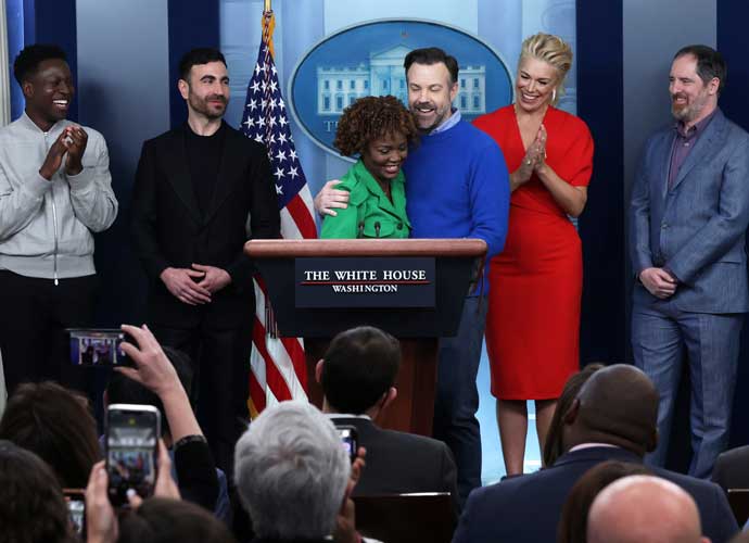 WASHINGTON, DC - MARCH 20: Comedian Jason Sudeikis of the Apple TV+ comedy series Ted Lasso embraces White House Press Secretary Karine Jean-Pierre as other cast members (L-R) Toheeb Jimoh, Brett Goldstein, Hannah Waddingham and Brendan Hunt look on during a White House daily news briefing at the James S. Brady Press Briefing Room on March 20, 2023 in Washington, DC. Sudeikis and the cast of Ted Lasso are at the White House to meet with President Joe Biden and first lady Jill Biden to discuss “the importance of addressing your mental health to promote overall well-being.” (Photo by Alex Wong/Getty Images)