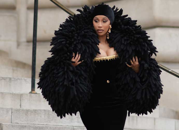 PARIS, FRANCE - JULY 03: Cardi B wears a black velvet scarf as a hat from Schiaparelli, gold large ears and white pearls pendant earrings from Schiaparelli, a black velvet with embroidered gold metallic shoulder-off borders / long tube dress from Schiaparelli, gold large bracelets from Schiaparelli, pumps heels shoes , a black fluffy oversized puffy jacket from Schiaparelli, outside Schiaparelli, during the Haute Couture Fall/Winter 2023/2024 as part of Paris Fashion Week on July 03, 2023 in Paris, France. (Photo by Edward Berthelot/Getty Images)