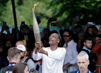 PARIS, FRANCE - JULY 26: US rapper Snoop Dogg holds the torch as part of the 2024 Paris Olympic Games Torch Relay, in Saint-Denis on July 26, 2024 in Paris, France. (Photo by Stephane De Sakutin - Pool/Getty Images)